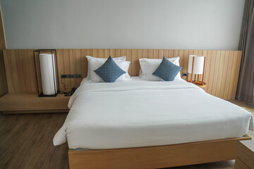 white mattress on minimal double bed with long big lamps at bedside in hotel bedroom