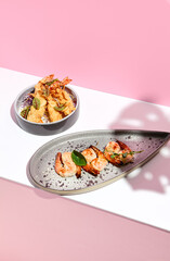 Restaurant seafood - Shrimp Grill Seafood Plate. Appetizer food plate on white table with pink wall. Day sunlight with hard shadow of monstera palm leaves. Summer or spring food concept.