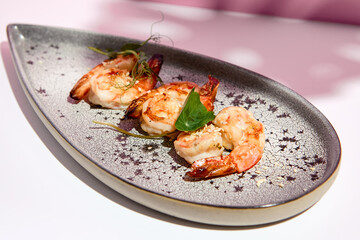 Restaurant seafood - Shrimp Grill Seafood Plate. Appetizer food plate on white table with pink wall. Day sunlight with hard shadow of monstera palm leaves. Summer or spring food concept.
