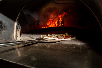 Traditional way baked wood fired oven Italian pizza bakery pizzeria. Restaurant chef takes pizza...