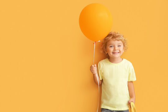Cute little boy with air balloon on color background