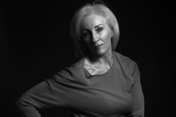 Classic black-and-white dramatic portrait of elderly blonde woman in Studio on black background