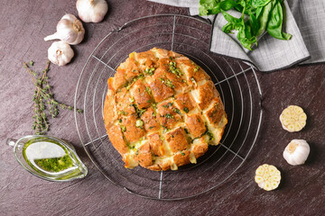 Tasty garlic bread with herbs on dark background