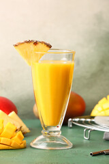 Glass of tasty mango smoothie on color background