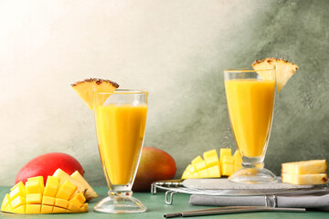 Glasses with tasty mango smoothie on color background
