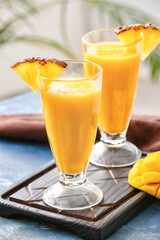 Glasses of tasty mango smoothie on color background