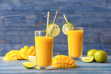 Glasses of tasty mango smoothie on color wooden background