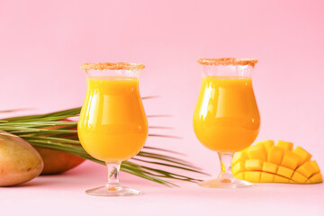 Glasses of tasty mango smoothie on color background