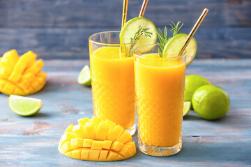 Glasses of tasty mango smoothie on color wooden background