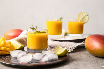 Glasses of tasty mango smoothie on light background