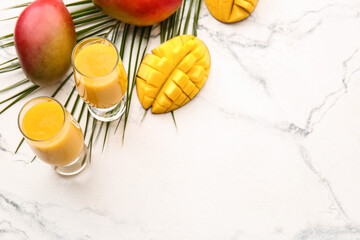 Glasses of tasty mango smoothie on light background