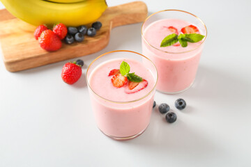 Glasses of tasty berry smoothie on light background