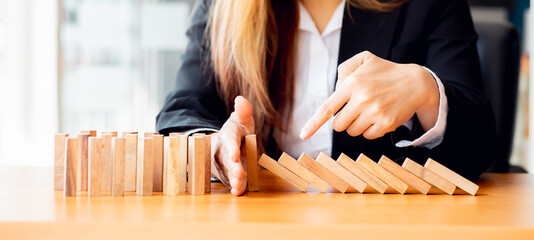 Business woman Hand stopping wooden domino business crisis effect or risk protection concept