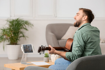 Young man taking music lessons online at home