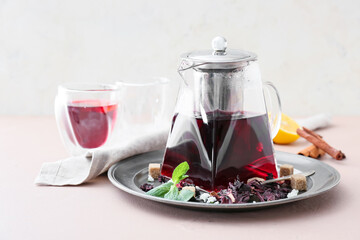 Teapot of hot hibiscus tea on light background