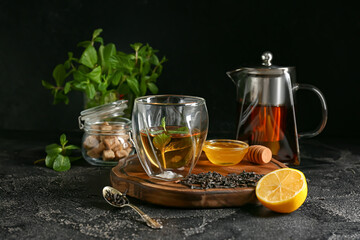 Glass of hot tea with lemon and honey on dark background