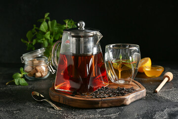 Teapot and glass of hot tea on dark background