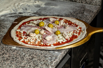 Man cook pizza, pizza on a pizza shovel. Chef taking raw pizza on metal shovel for baking in the oven in traditional restaurant
