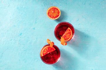 Orange cocktails, overhead flat lay shot on a blue background with a place for text