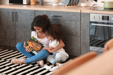 Cute African-American sisters reading book at home