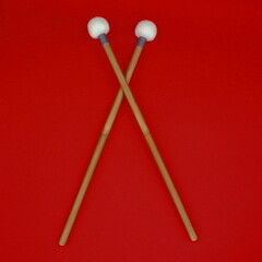 Crossed timpani mallets on a red background.