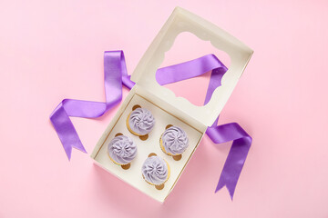 Box with tasty cupcakes on color background
