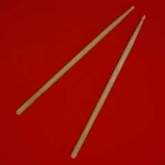 Percussion drumsticks on a red background.