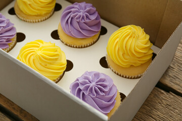 Box with tasty cupcakes on table, closeup