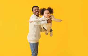 Portrait of happy African-American father and his little daughter on color background