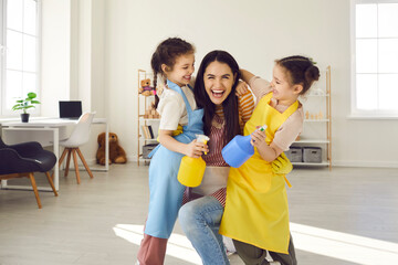 Portrait of a happy mother with two daughters having fun and fooling around while cleaning the...
