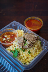 Roasted meat served with rice and chillies tamarind sauce and curry gravy in a take out container. Malaysian traditional cuisine, Nasi Daging Utara.