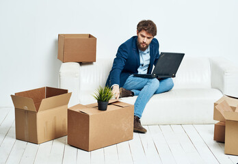 Business man sitting on the couch with laptop boxes with things unpacking office official