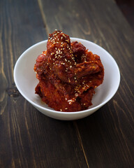 Chunks of fried chicken in a spicy sauce and sesame seeds. Food Korean cuisine on a wooden background.