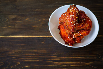 Chunks of fried chicken in a spicy sauce and sesame seeds. Food Korean cuisine on a wooden background.