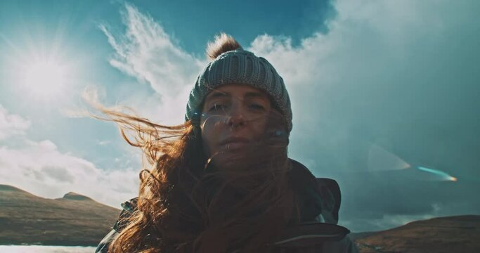 Young woman staring at the camera in a windy landscape