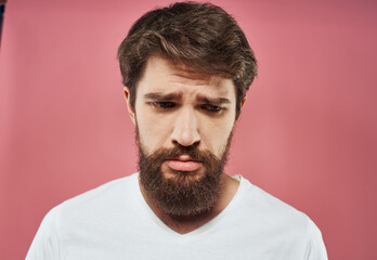 Obraz premium Sad man crying on a pink background in a white t-shirt cropped view