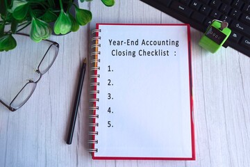 Text on notebook with glasses, pen, keyboard and green plant on the table - Year end accounting closing checklist