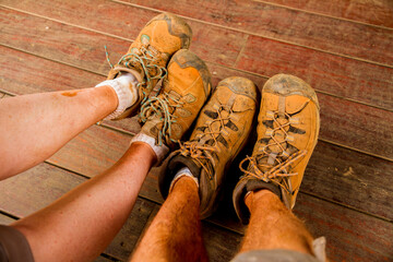Very dirty hiking boots covered in red orange dirt.