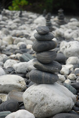 Fototapeta na wymiar Pebbles are piled on a volcanic rock by the sea. Zen concept. Copy space.