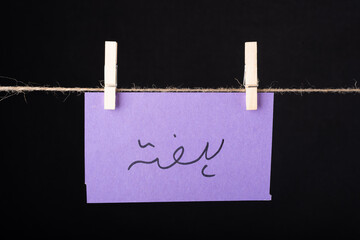  Translation Saturday in urdu word written on a Purple color sticky note hanging with a wire on black background