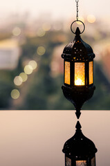 Hanging lantern with dusk sky and city bokeh light background for the Muslim feast of the holy month of Ramadan Kareem.