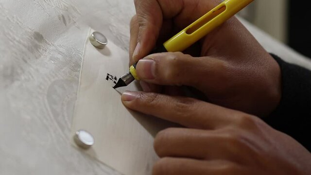 A close-up video of a Jewish artist writing letters of a Torah scroll in Hebrew (for the editor - the letters are random without meaning)