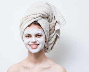 nude woman with white cream on her face and a towel on her head