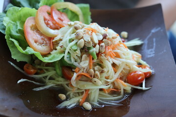 Thai papaya salad is not spicy. Thai style food, woman holding a plate with papaya salad.