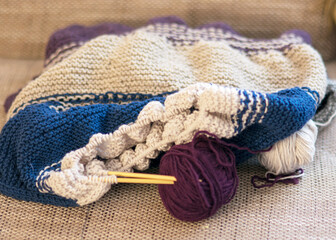 knitted colorful sweater with knitting needles and a ball of yarn