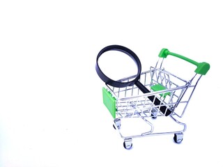 Picture of magnifying glass inside a miniature trolley isolated on white background.