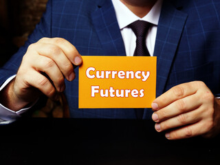 Business concept about Currency Futures with sign on orange business card in hand.