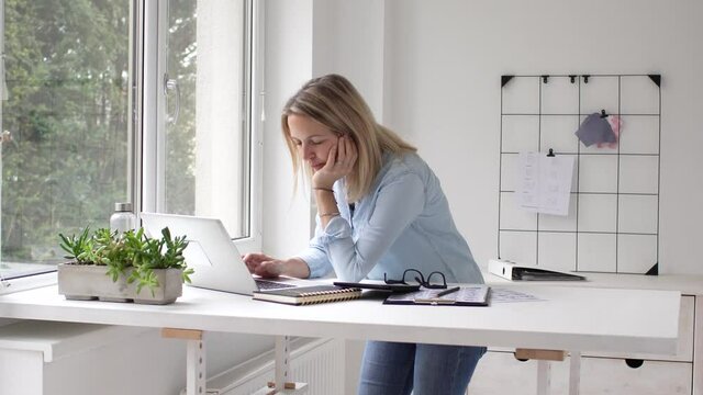 Businesswoman working at a standing workstation at a laptop in office