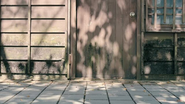 Luodong Forestry Culture Park at Luodong, Luodong Township, Yilan County, Taiwan - February 06, 2021: The sunlight on the wall of the wooden house. A bicycle pass by the house.