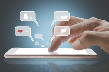 Closeup of person finger hand using a social media chat on a mobile phone with notification icons of like, message, comment, and star above smartphone screen.